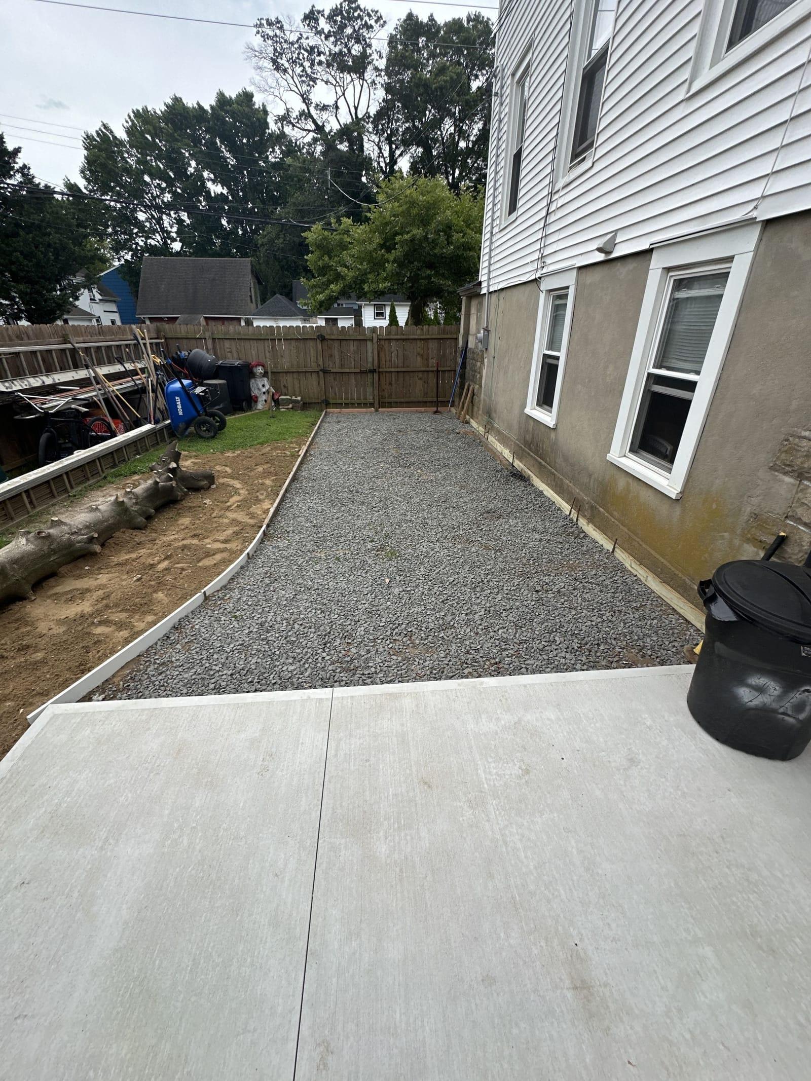 Compacted gravel base and forms beside freshly poured concrete patio in Central NJ
