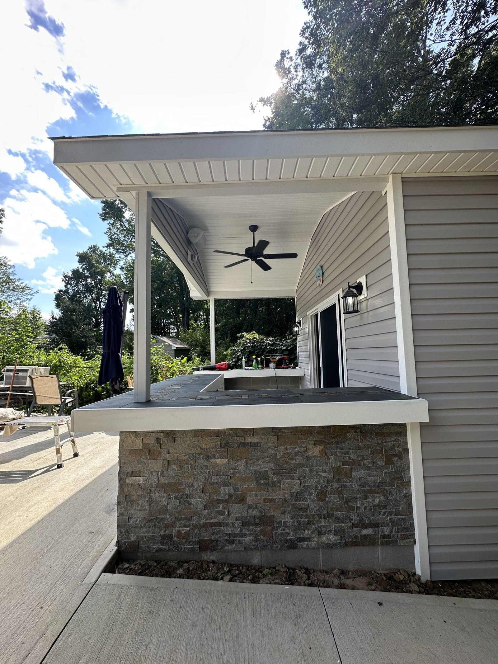Stone veneer outdoor bar detail with covered porch and ceiling fan